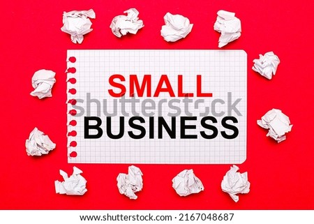 On a bright red background, white crumpled sheets of paper and a sheet of paper with the text SMALL BUSINESS