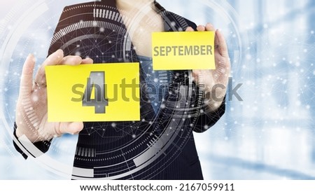 September 4th. Day 4 of month, Calendar date. Business woman hand hold yellow sheet with calendar date on blurred office background.  Autumn month, day of the year concept
