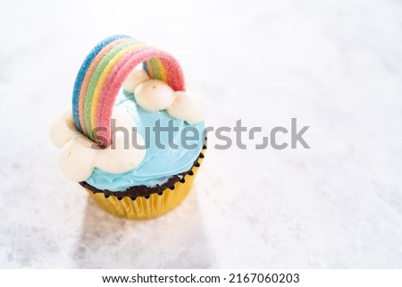 Chocolate cupcakes decorated with blue buttercream frosting and rainbow for unicorn theme birthday party.