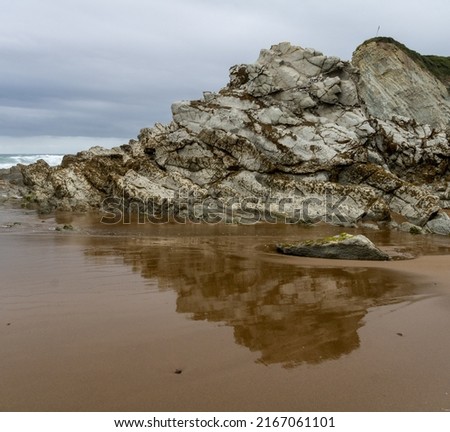 EMPTY NORTHERN BEACH WITH ROCKS WITH CLOUDY SKY 