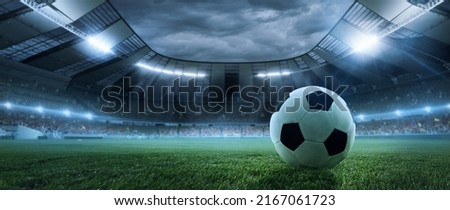 After game. Closeup soccer ball on grass of football field at crowded stadium with spotlights at evening time. Concept of sport, art, energy, power. Poster for ad, design Royalty-Free Stock Photo #2167061723