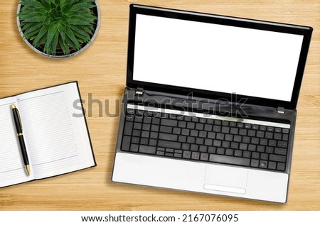 Laptop, notebook and pen with a potted plant on a wooden background. Flat lay. Mock up. The concept of office work and education.