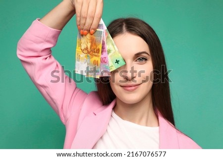 Beautiful young woman holding swedish krona banknotes near face, smiling happy with open mouth  Royalty-Free Stock Photo #2167076577