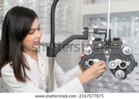 Young ophthalmologist doing visual test for customer using Bifocal Optometry eyesight measurement device in optical center, eyecare concept. Royalty-Free Stock Photo #2167077875