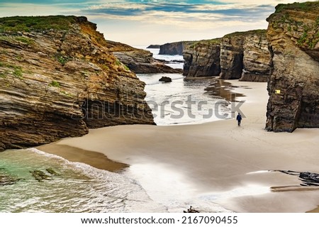People walking on Cathedrals Beach at low tide, Playa las Catedrales in Ribadeo, province of Lugo, Galicia. Cantabric coast in northern Spain. Tourist place. Royalty-Free Stock Photo #2167090455