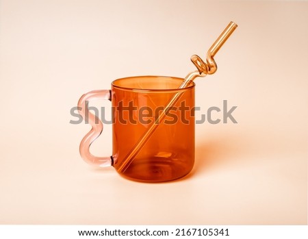 Summer glass cup design with twisted straw on beige background. High quality photo