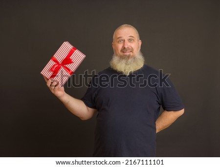 a man with a gray beard happily holding a gift in his hand on a black background