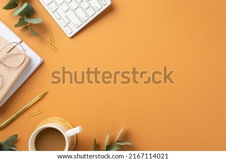 Business concept. Top view photo of workspace white keyboard copybooks stylish glasses gold pen clips cup of hot drinking and eucalyptus on isolated orange background with empty space Royalty-Free Stock Photo #2167114021