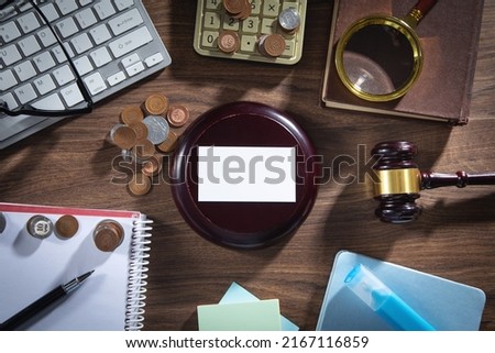 Empty business card with judge gavel and business objects.