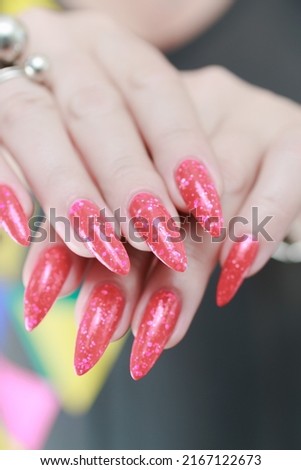 Female hands with long nails and neon pink nail polish