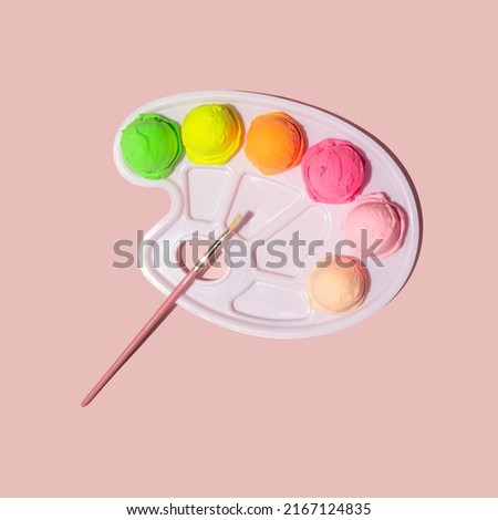 Colorful pastel ice cream balls and paint palette on light pink background. Creative food concept. Minimalistic sunny summer composition.