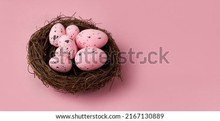 Closeup of Pink eggs in the nest on pink background.Copyspace banner