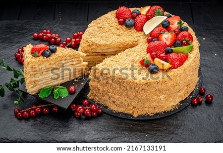 Napoleon cake decorated with berries and fruits. Delicious homemade dessert on a dark background. Royalty-Free Stock Photo #2167133191