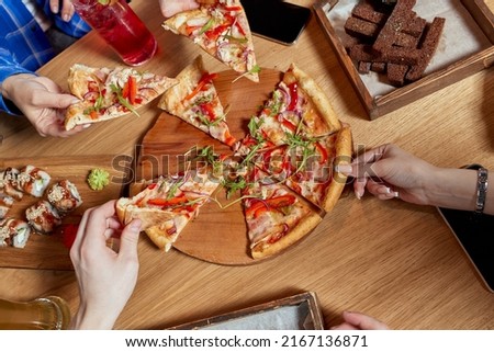 Image of teenage friends hands taking slices of pizza.