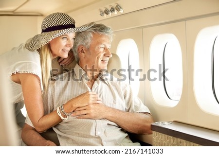 Taking a luxury trip. Smiling senior couple on an airplane looking out the window. Royalty-Free Stock Photo #2167141033