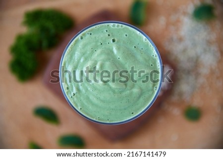 A green smoothie restores my body to factory settings. Overhead shot of a green health smoothie on a wooden board.