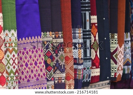 Traditional Laotian fabrics for sale in the early morning market at Luang Prabang, Laos. Royalty-Free Stock Photo #216714181