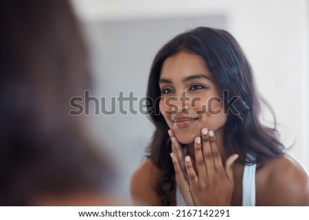 Your face will show you inner glow. Shot of a beautiful young woman admiring herself in the mirror at home. Royalty-Free Stock Photo #2167142291