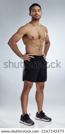 Feeling strong and muscular. Shot of a handsome young man against a studio background. Royalty-Free Stock Photo #2167142473