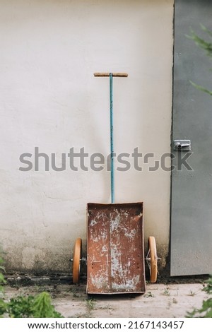 An old two-wheeled rusty cart stands near a house in the village.