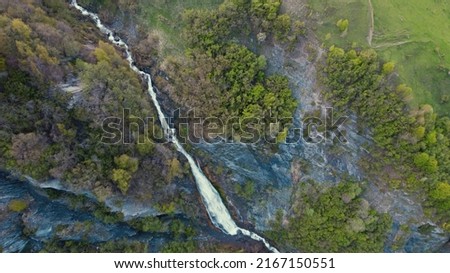 Mountain stream flowing fast between green forest trees. Aerial outdoor drone shot. High quality photo