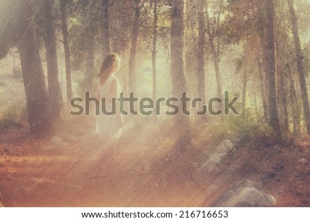 surreal blurred background of young woman stands in forest. abstract and dreamy concept. image is textured 