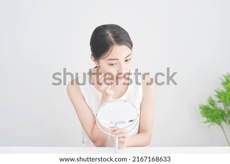 Asian woman looking in the mirror at home Royalty-Free Stock Photo #2167168633