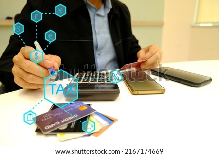Businessman takes or holding a pen in right hand, takes a credit card in left hand and calculates taxes of 
 property or real estate or saving with a calculator.