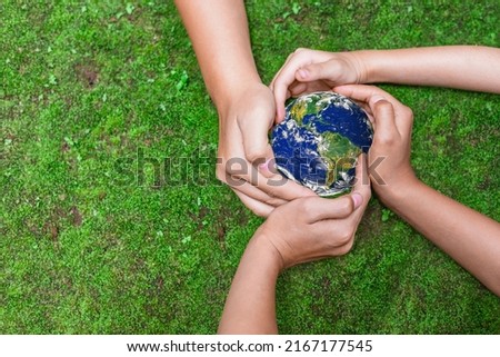 Environment conservation concept. Young children hands holding globe on green nature background for sustainable development goal.  world image by NASA Royalty-Free Stock Photo #2167177545