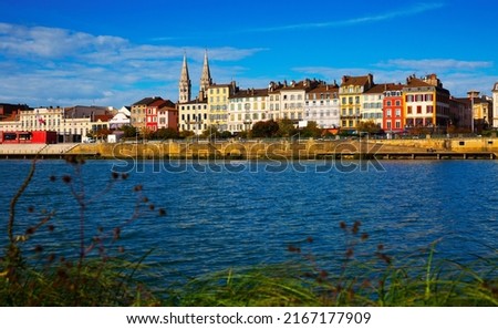 View of Macon cityscape across Saone river on blue autumn sky as background, France..