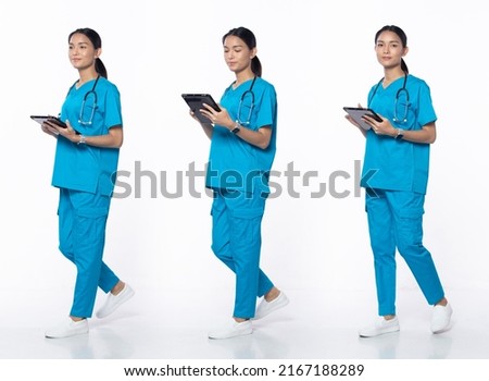 Full length 20s young Asian Woman clinic Nurse, walking forward left right, wear blue dress pants shoes stethoscope. Smile Hospital female hold patient chart over white background isolated