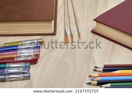 books pencils fountain pens and brushes for drawing on the table concept education school. High quality photo