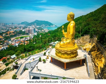 Ariel view Golden Buddha statue's hand holding lotus at Chon Khong Monastery which attracts tourists to visit spiritually on weekends in Vung Tau, Vietnam. Travel concept.