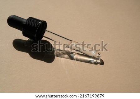 A pipette of cosmetic gel on a beige background.