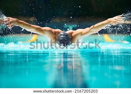 Perfect butterfly stroke. Shot of a male swimmer doing the butterfly stroke toward the camera. Royalty-Free Stock Photo #2167205203