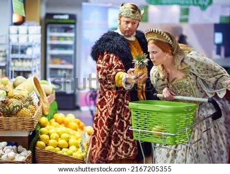 What does one do with this strange item. A view of a king and queen in the supermarket feeling puzzled by the produce. Royalty-Free Stock Photo #2167205355