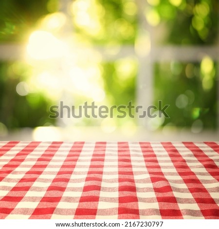 Table with red checkered cloth indoors. Space for design