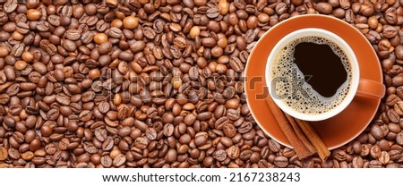 Cup of hot coffee with cinnamon on roasted beans. Banner for design