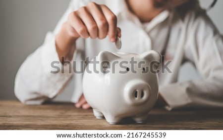  Hand holding coin with pig piggy bank. Saving and financial accounts concept
