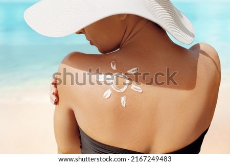 Sun Protection. Beauty Woman Applying Sun Cream Creme on Tanned  Shoulder In Form Of The Sun. . Skin Care. Girl Using Sunscreen to Skin. Royalty-Free Stock Photo #2167249483