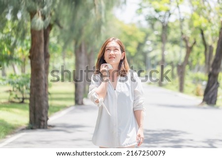 Woman walking in the park having sunstroke in summer hot weather, Young pretty girl drying sweat using a wipe on a warm summer day in a park Royalty-Free Stock Photo #2167250079