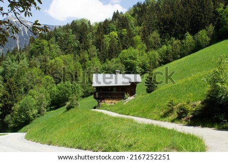 Green grass spring alpine valley with old wooden farm house of Massif du Beaufortain Savoie Mont Blanc region France
