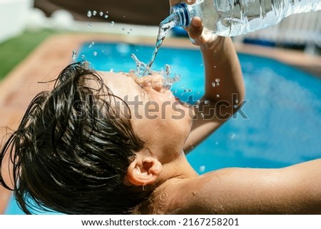 Heat wave. Splashing pouring spilling throwing water in the face with a bottle due to high temperatures in summer. Pool and water to withstand the heat wave during the holiday season. heat stroke from Royalty-Free Stock Photo #2167258201