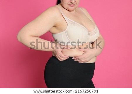 Obese woman on pink background, closeup. Weight loss surgery Royalty-Free Stock Photo #2167258791