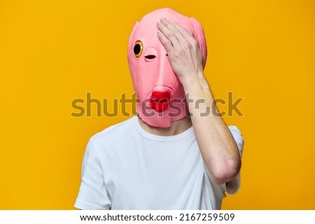 a man in a funny pink mask closes his left eye with his hand