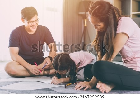 Asian family parents playing with daughter in living room together child drawing cartoon in paper.