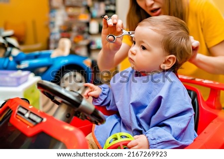 Baby's first haircut. Cute little boy at the professional children's hairdresser. High quality photo Royalty-Free Stock Photo #2167269923