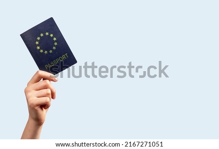 Banner with woman hand holding passport on blue background. Female with travel document. Identity, nationality verification. Place for text. High quality photo Royalty-Free Stock Photo #2167271051
