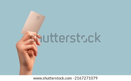 Banner with hand holding credit card mockup with chip on blue background. Buying at stores, making transactions at terminals. Secure payments. High quality photo