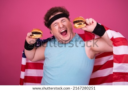 Sport, fitness and healthy lifestyle. Funny fat guy goes in for sports and eats a hamburger.	